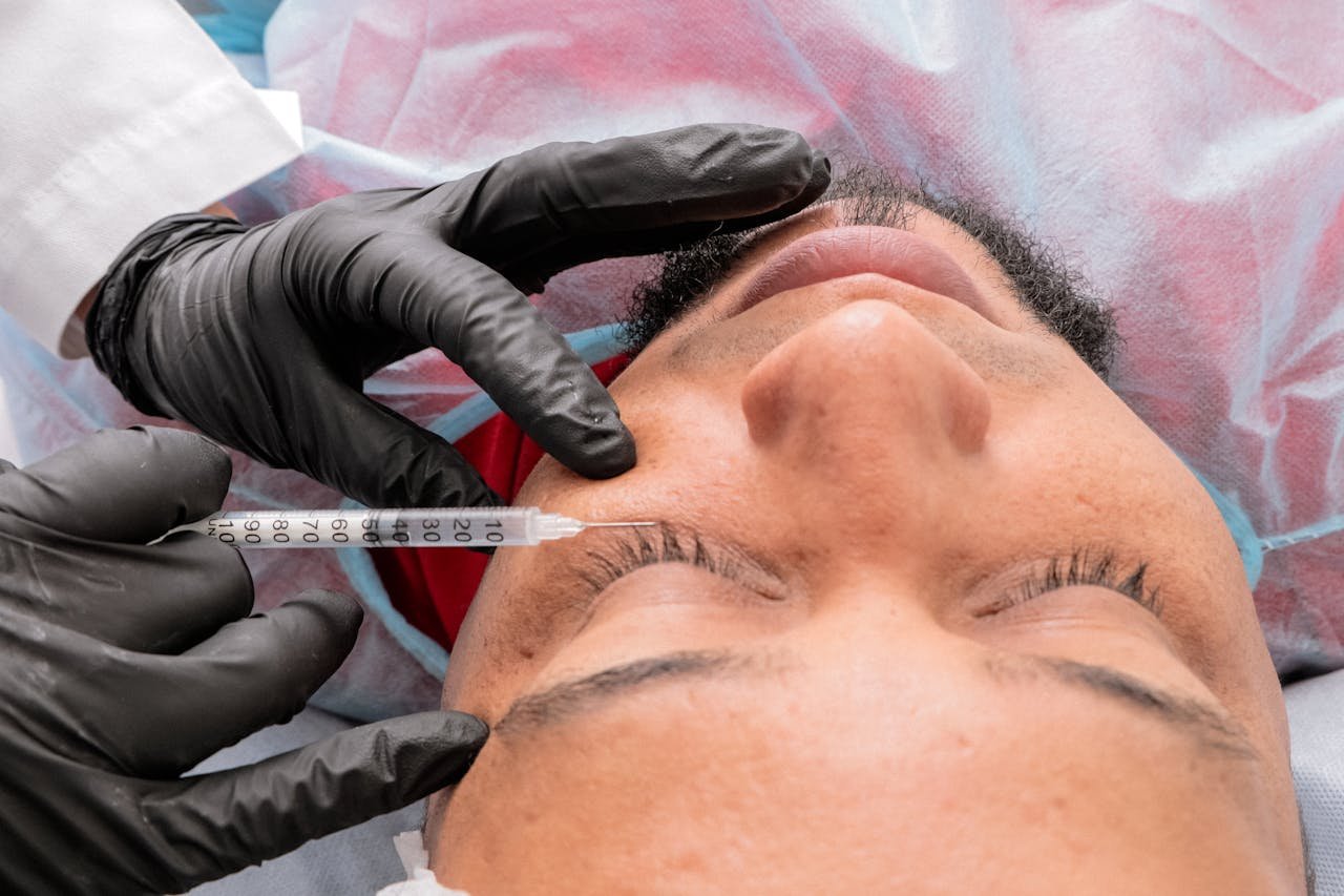 our-story-02 Man receiving facial treatment with syringe in medical facility.